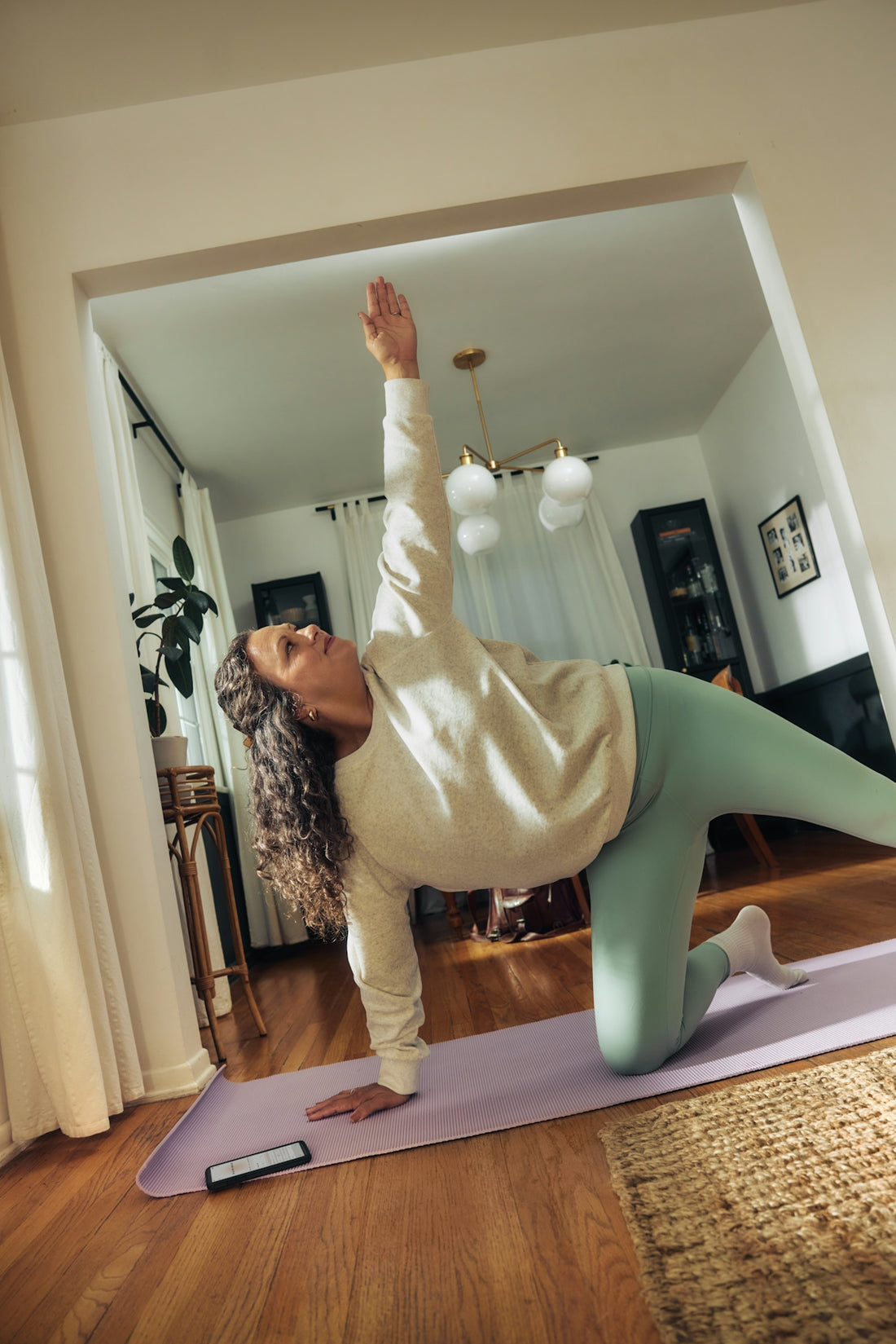 A woman does a yoga pose on a mat.
